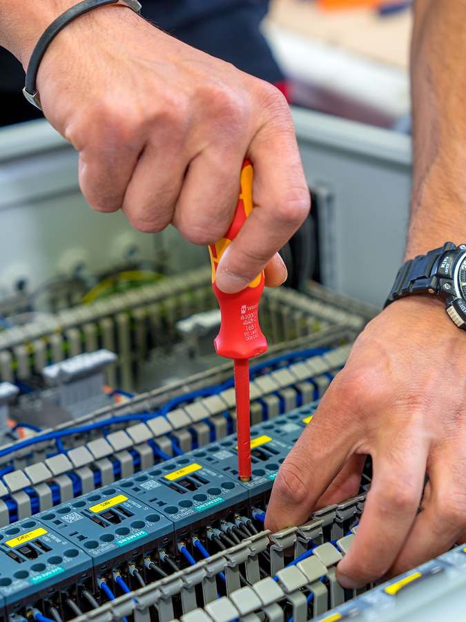 Elektriker verdrahtet Schütze und Klemmen in einem Antriebs-Schaltschrank